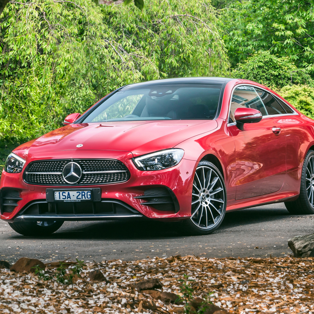 Красный автомобиль Mercedes-Benz E 300 AMG, 2020 года у дома осенью