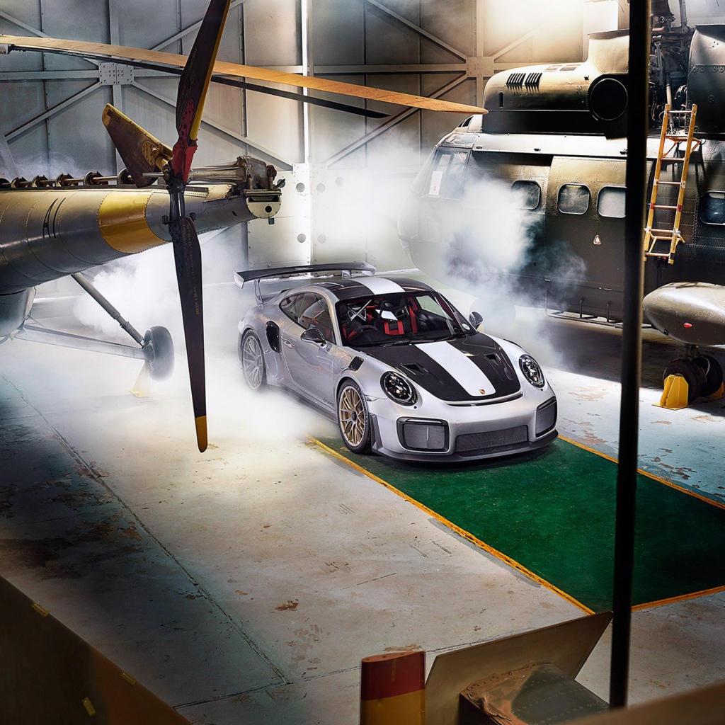 Автомобиль Porsche 911 GT2 RS в ангаре с вертолетами