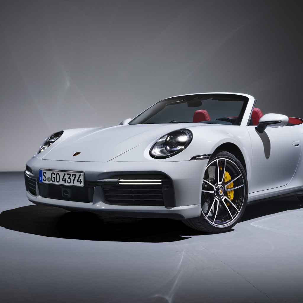 Белый кабриолет Porsche 911 Turbo S 2020 года на сером фоне