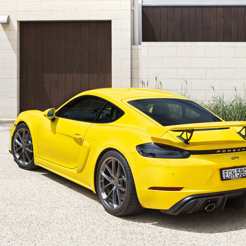 Желтый автомобиль Porsche 718 Cayman GT4, 2020 года у гаража 