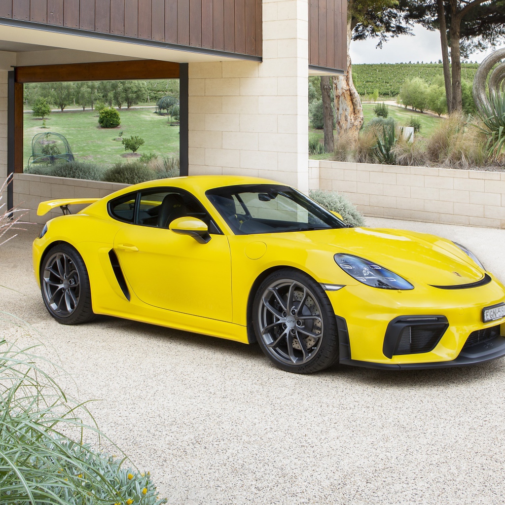 Желтый автомобиль Porsche 718 Cayman GT4, 2020 года у дома