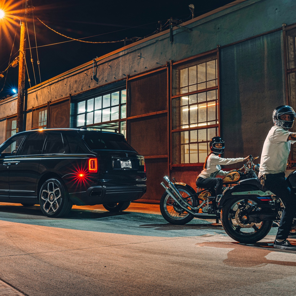 Черный автомобиль Rolls-Royce Cullinan, 2020 года у гаража с байкерами