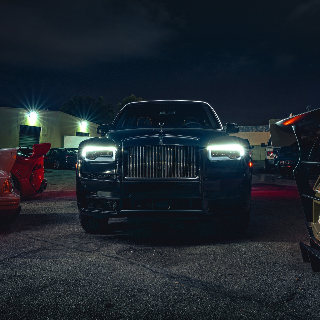 Черный дорогой автомобиль  Rolls-Royce Cullinan, 2020 года с включенными фарами