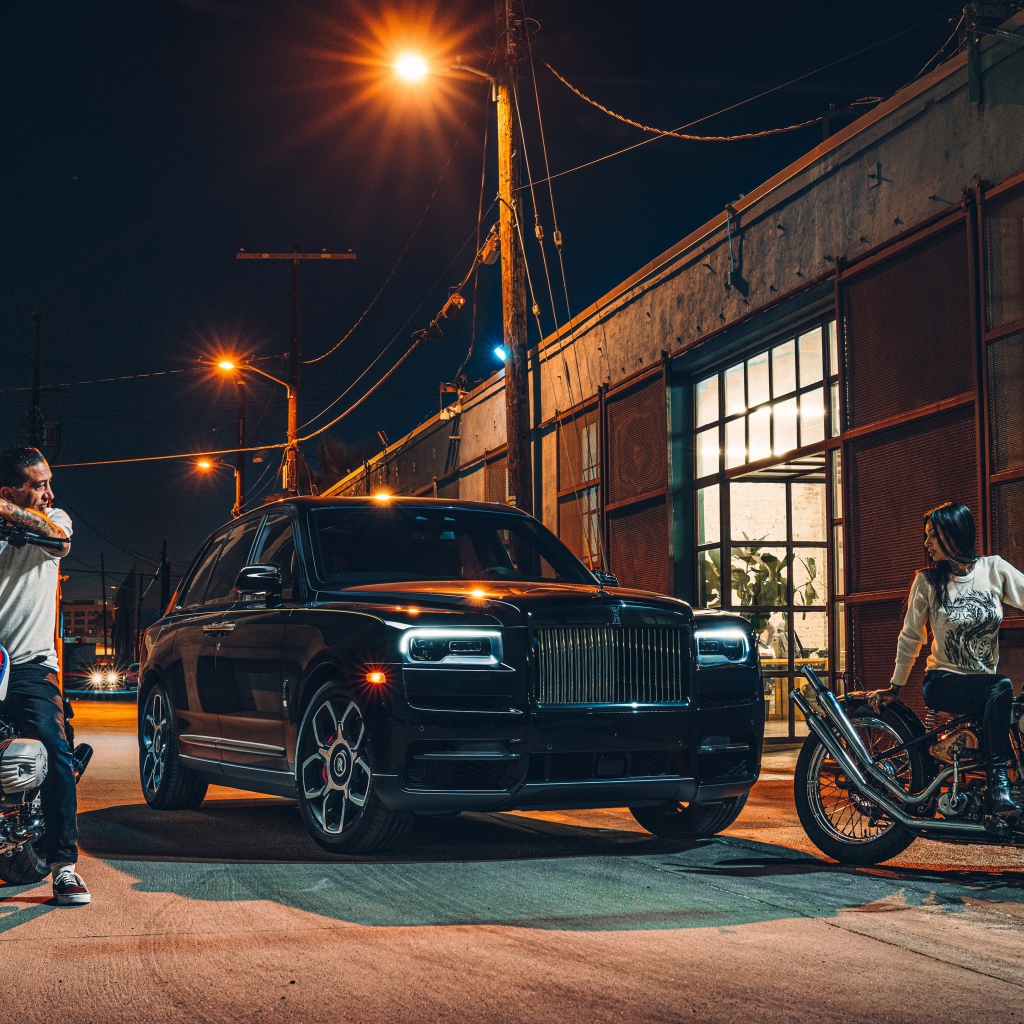 Черный стильный автомобиль Rolls-Royce Cullinan на улице города с байкерами
