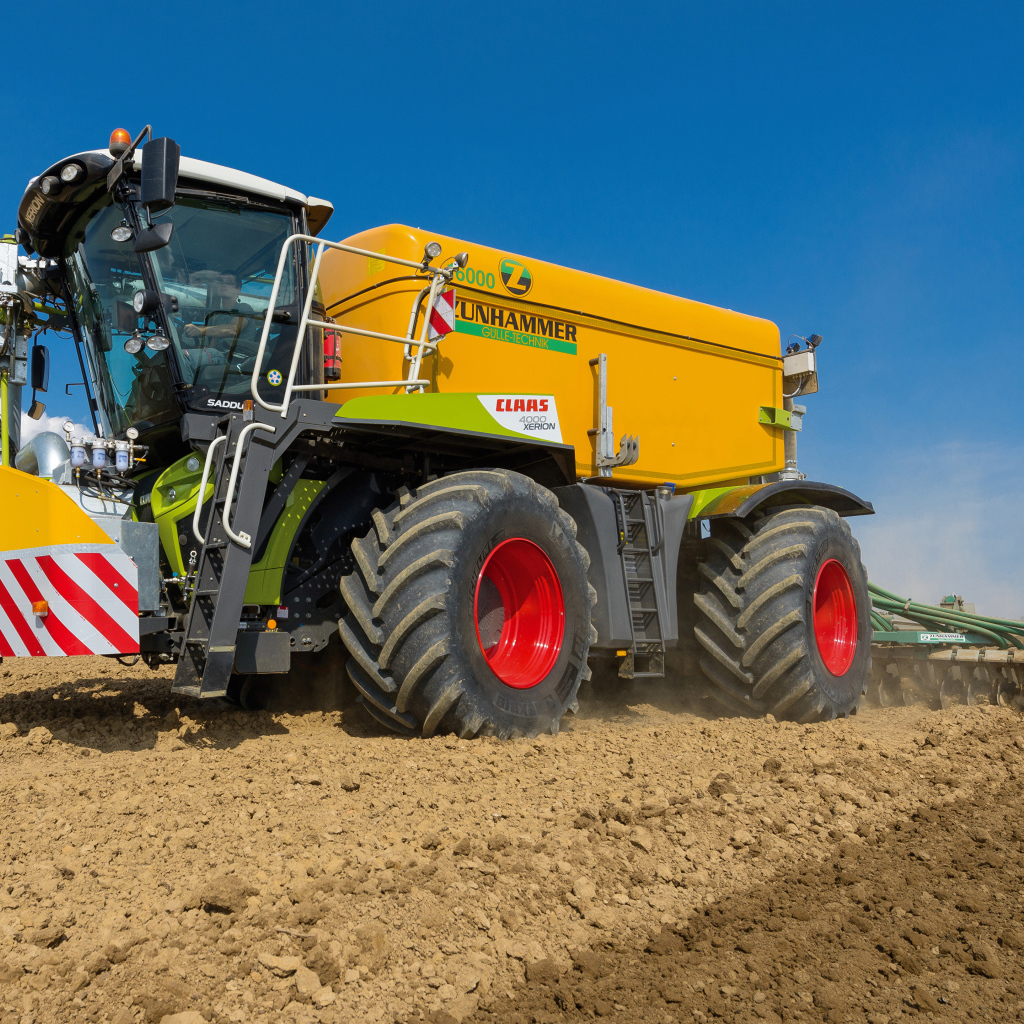 Большой комбайн пашет поле под голубым небом