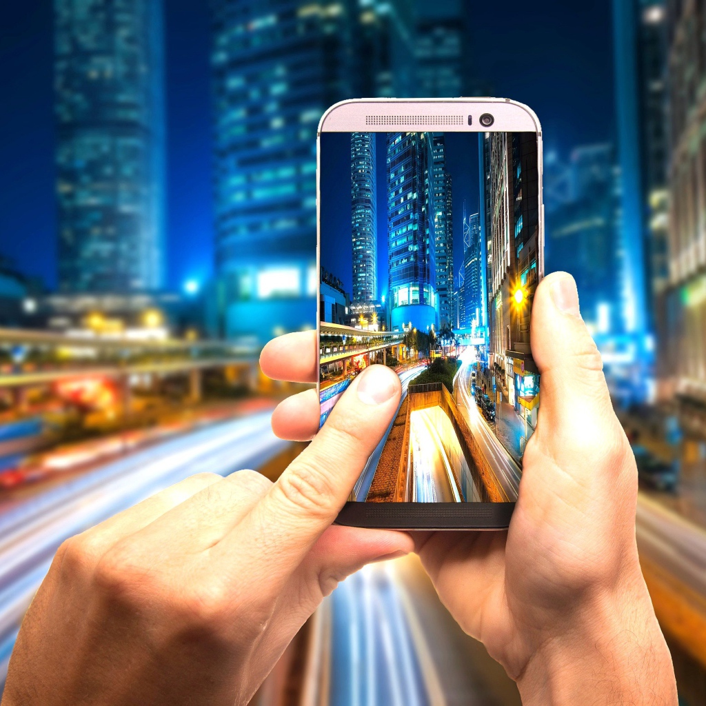 Мужчина делает фото ночного города на смартфон 
