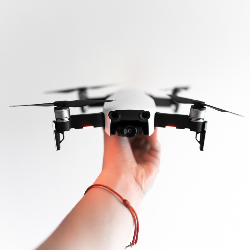 Белый квадрокоптер в руке на белом фоне