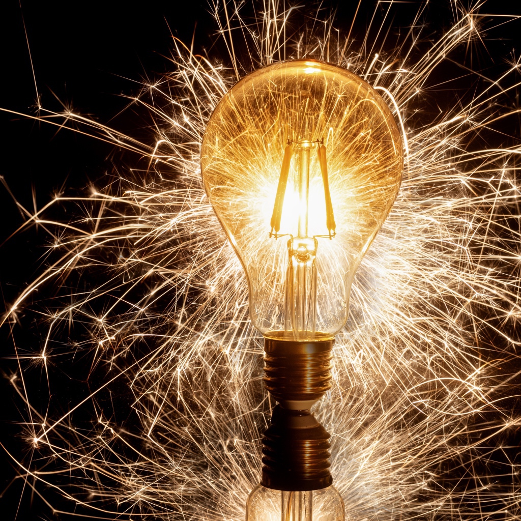 A lit lamp on a black background with sparks