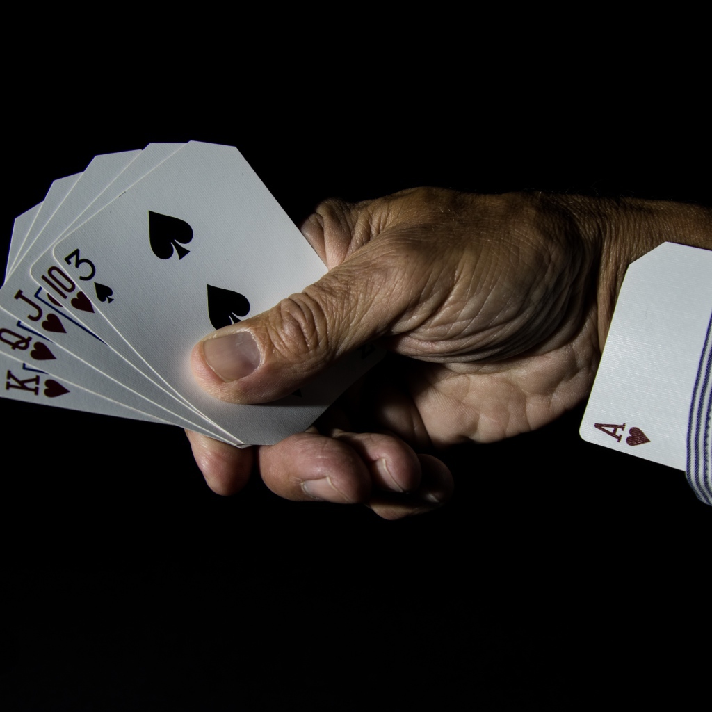 Туз в рукаве у шулера на черном фоне 