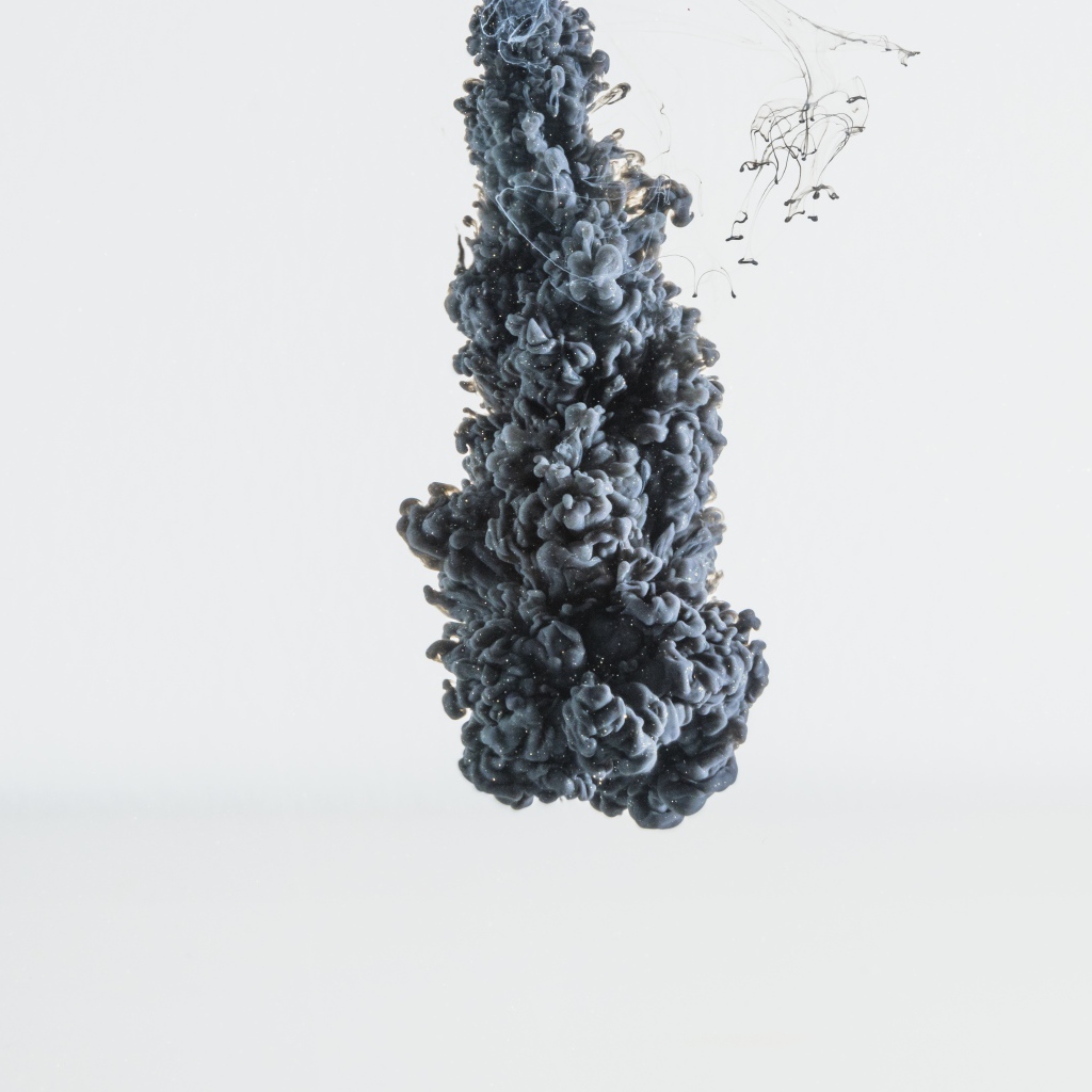 Черная краска растворяется в воде на белом фоне 