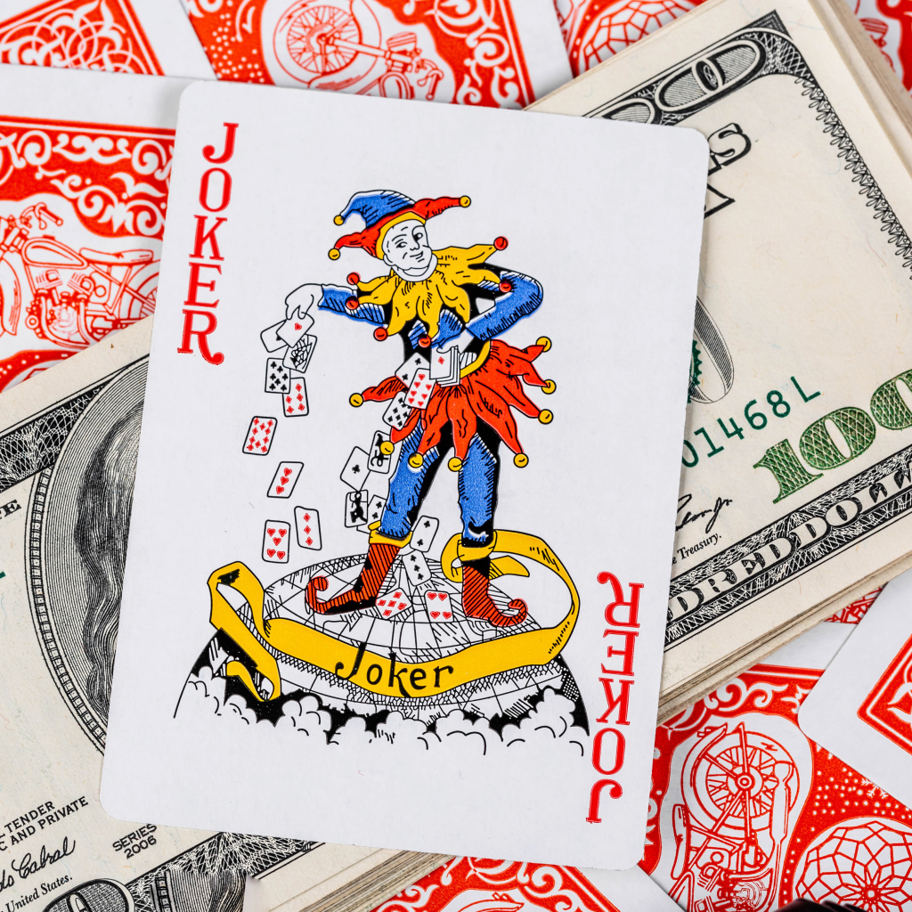 Карточный Джокер и пачка стодолларовых купюр