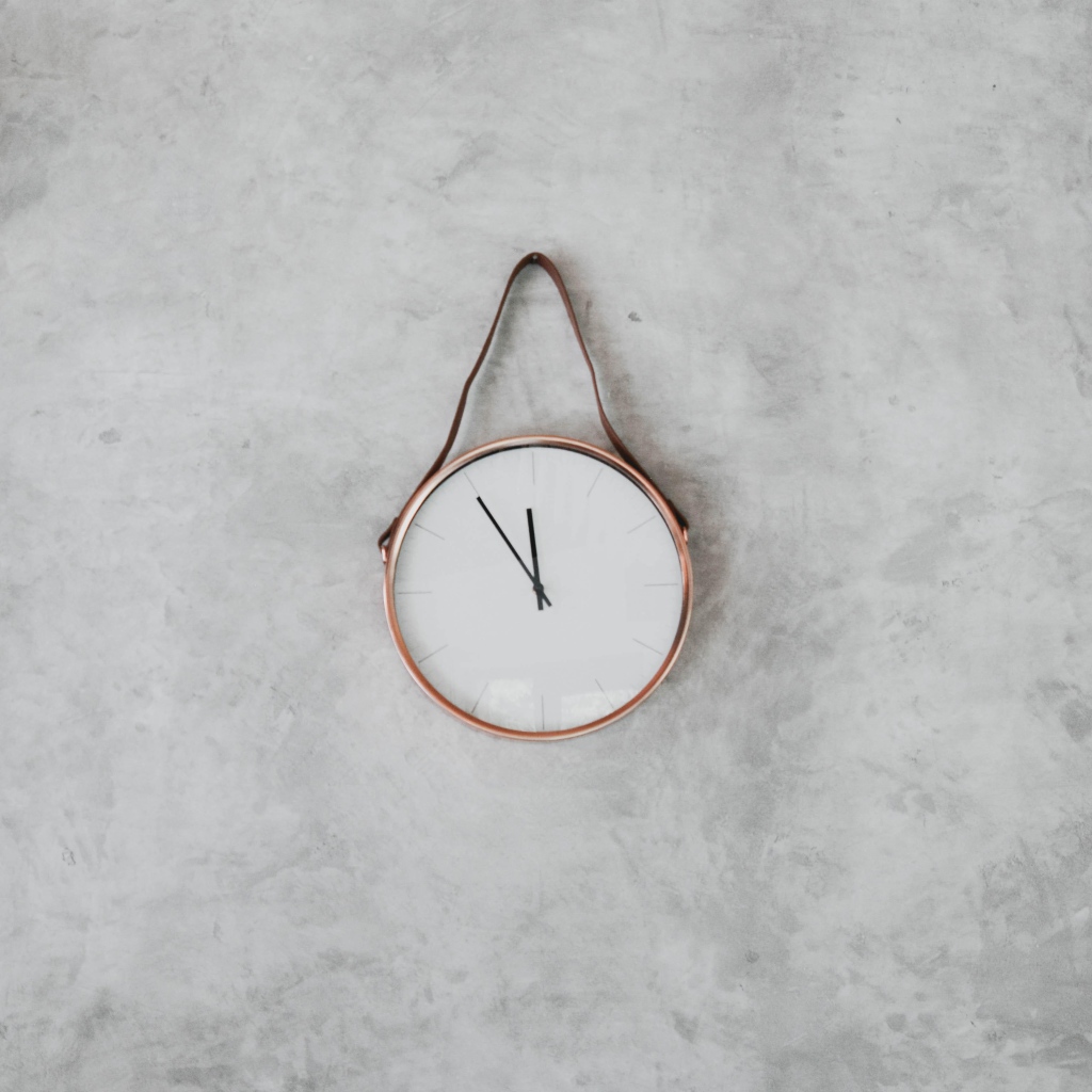 Часы с черными стрелками висят на серой стене 