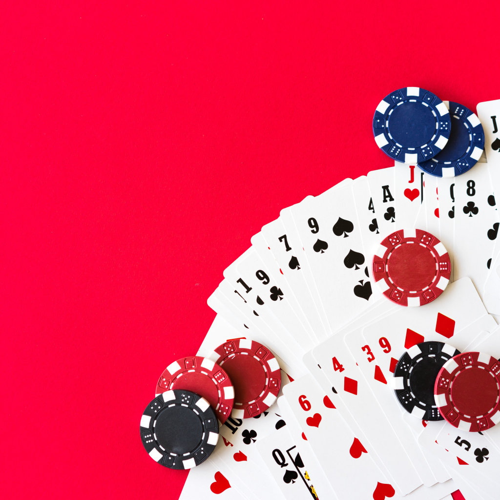 Колода карт и фишки для игры в покер на красном фоне