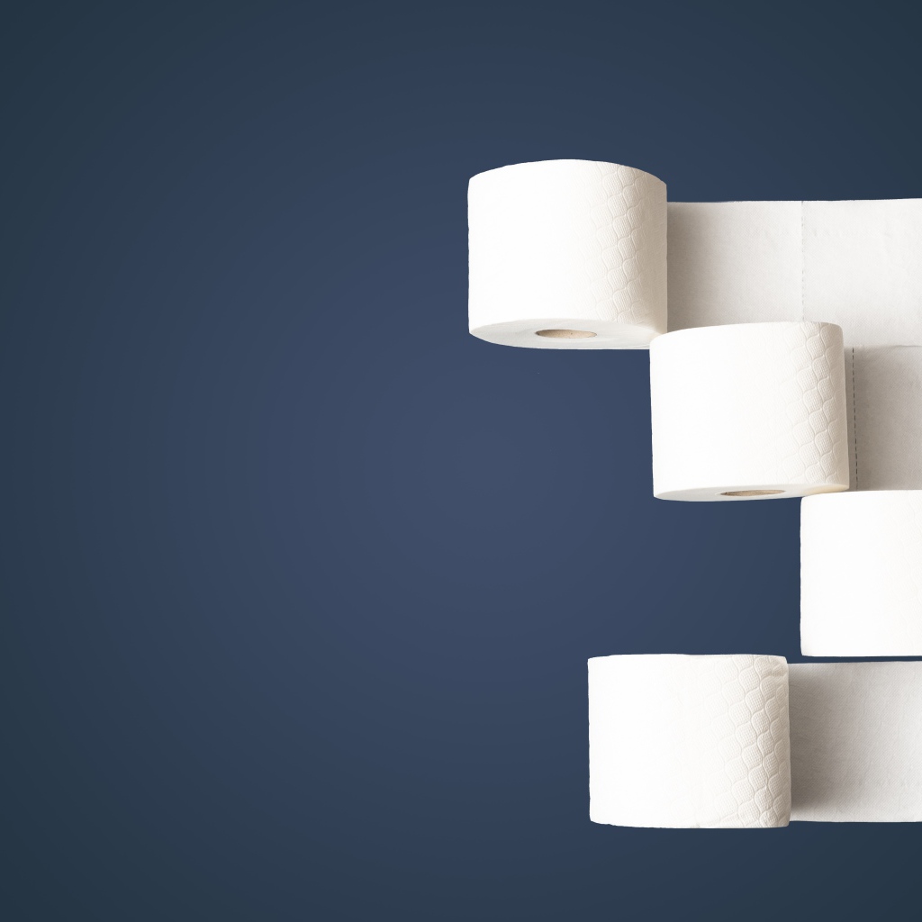 Четыре рулона белой туалетной бумаги на сером фоне