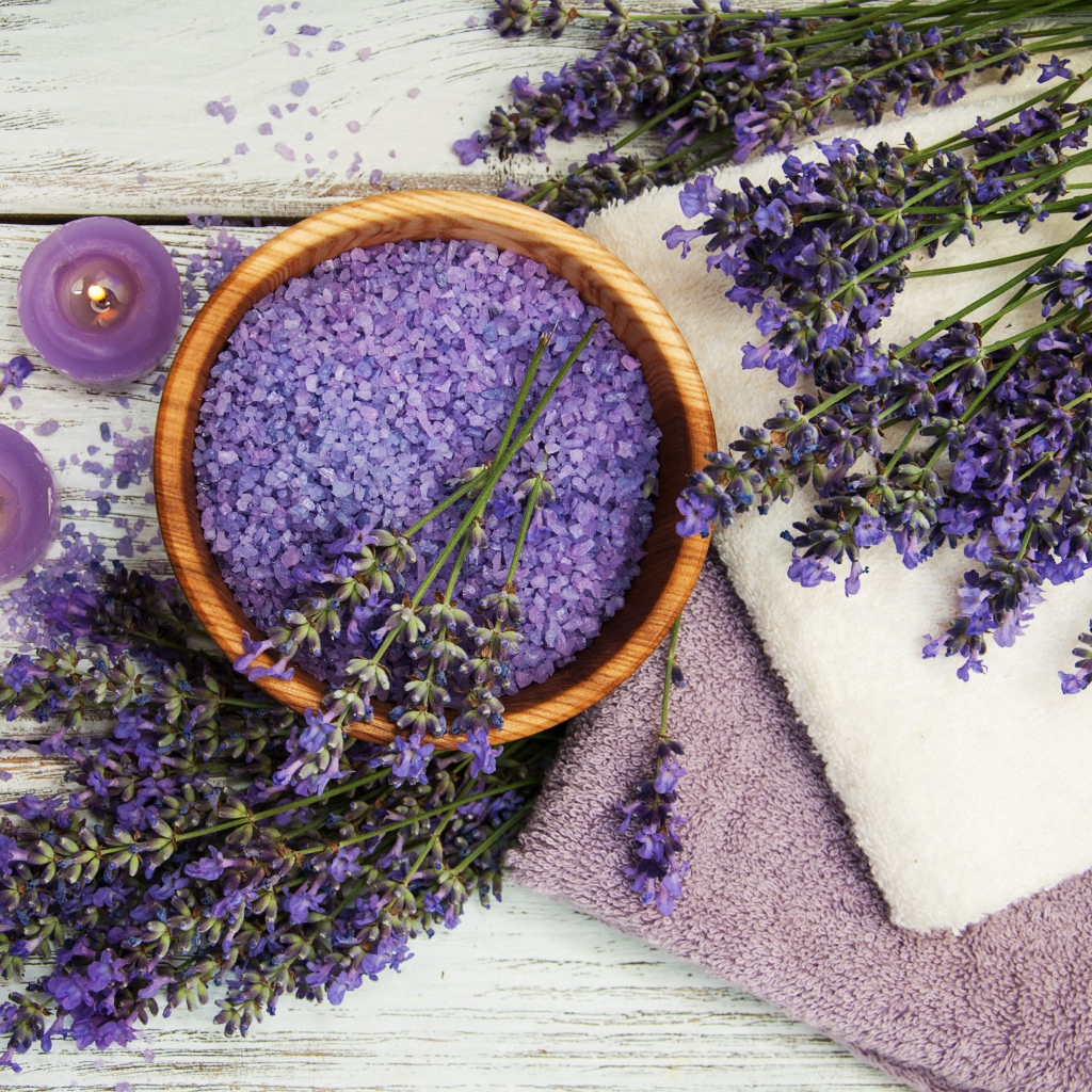 Ароматная соль, на столе с полотенцами, лавандой и зажженными свечами