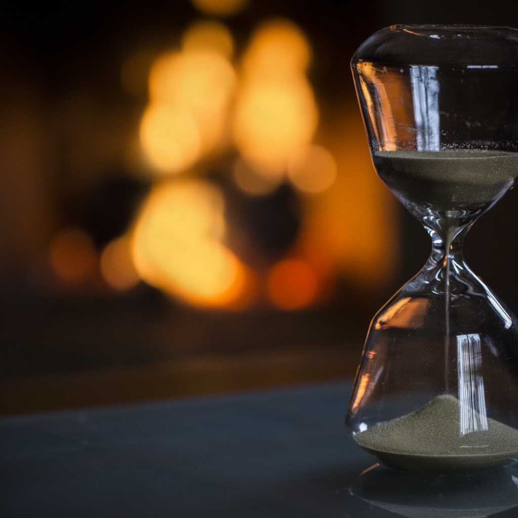 Стеклянные песочные часы на столе 