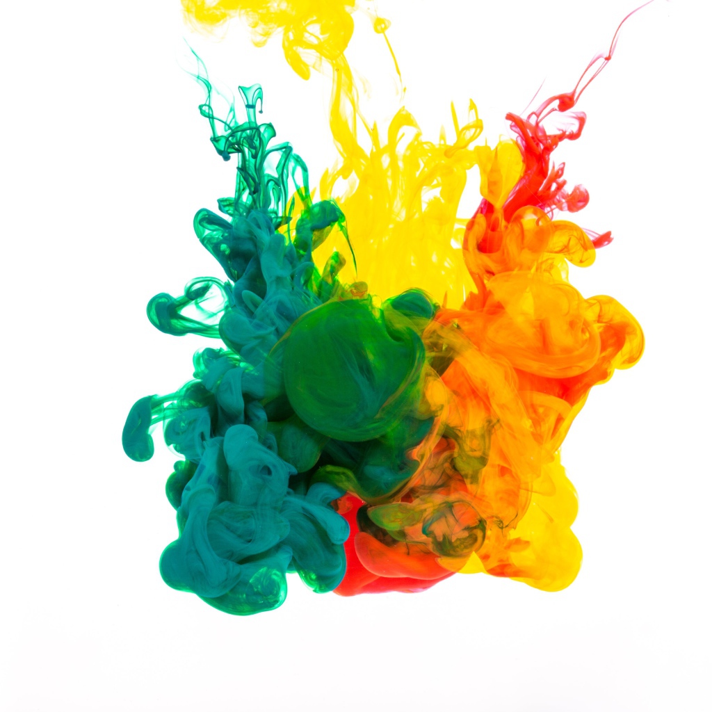 Зеленая и желтая краска растворяются в воде на белом фоне