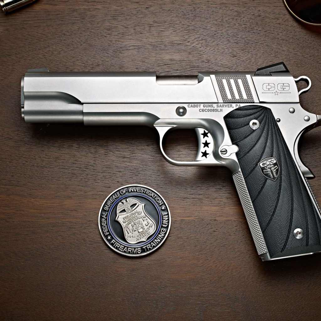 Gun Cabot 1911 lies on a table with glasses and a badge.