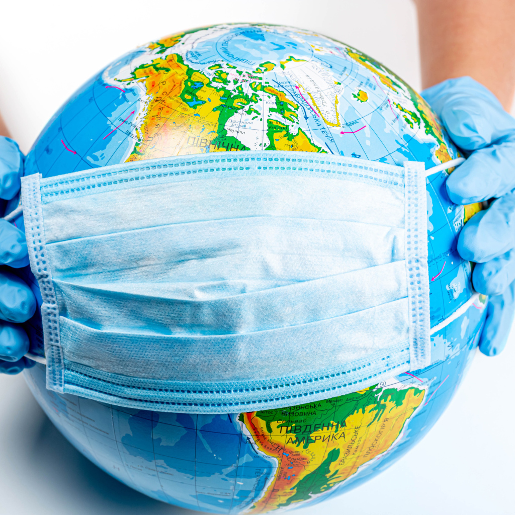 Руки одевают маску от коронавируса на глобус 