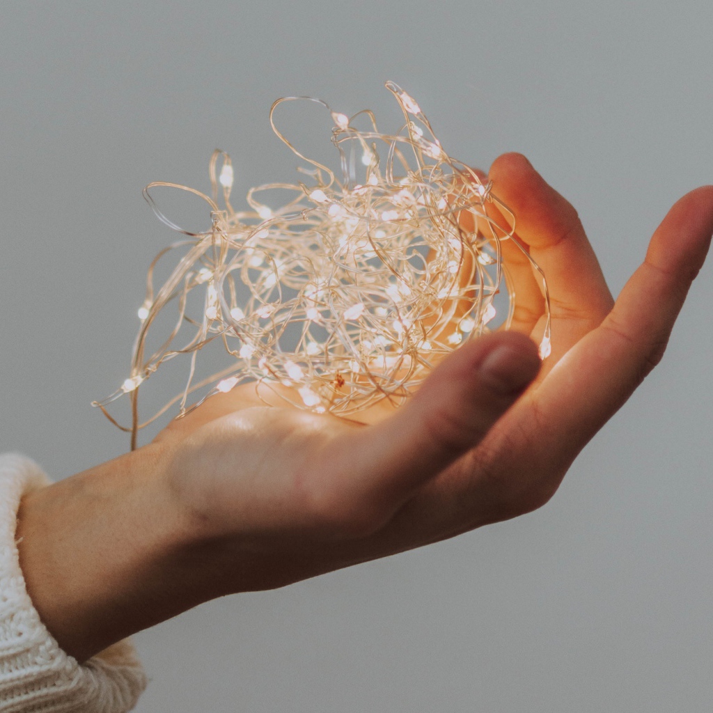 Включенная гирлянда в руке на сером фоне