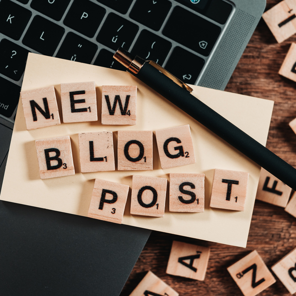 Надпись на английском New Blog Post возле ноутбука с ручкой 