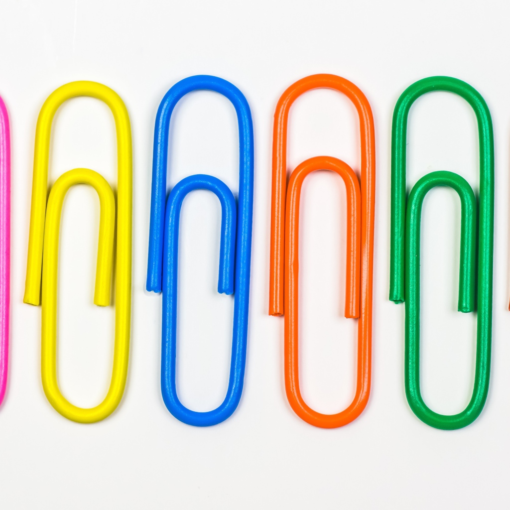 Multicolored paper clips on white background