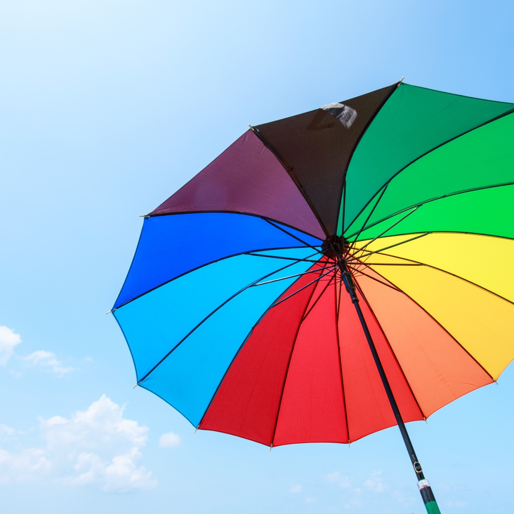 Разноцветный зонт на фоне голубого неба 