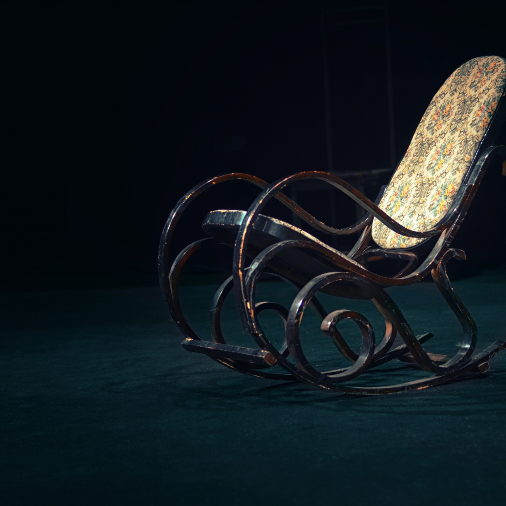 Старое кресло - качалка в темной комнате 