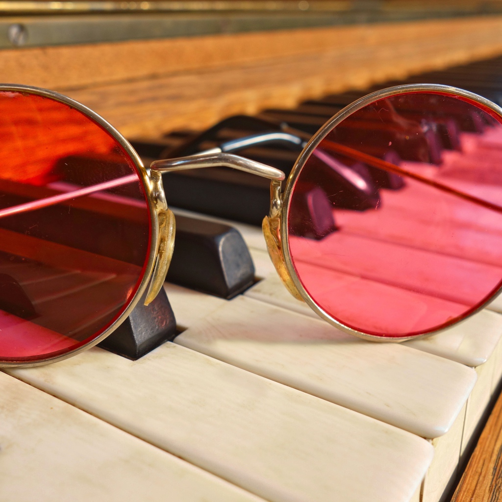 Розовые очки лежат на клавишах рояля