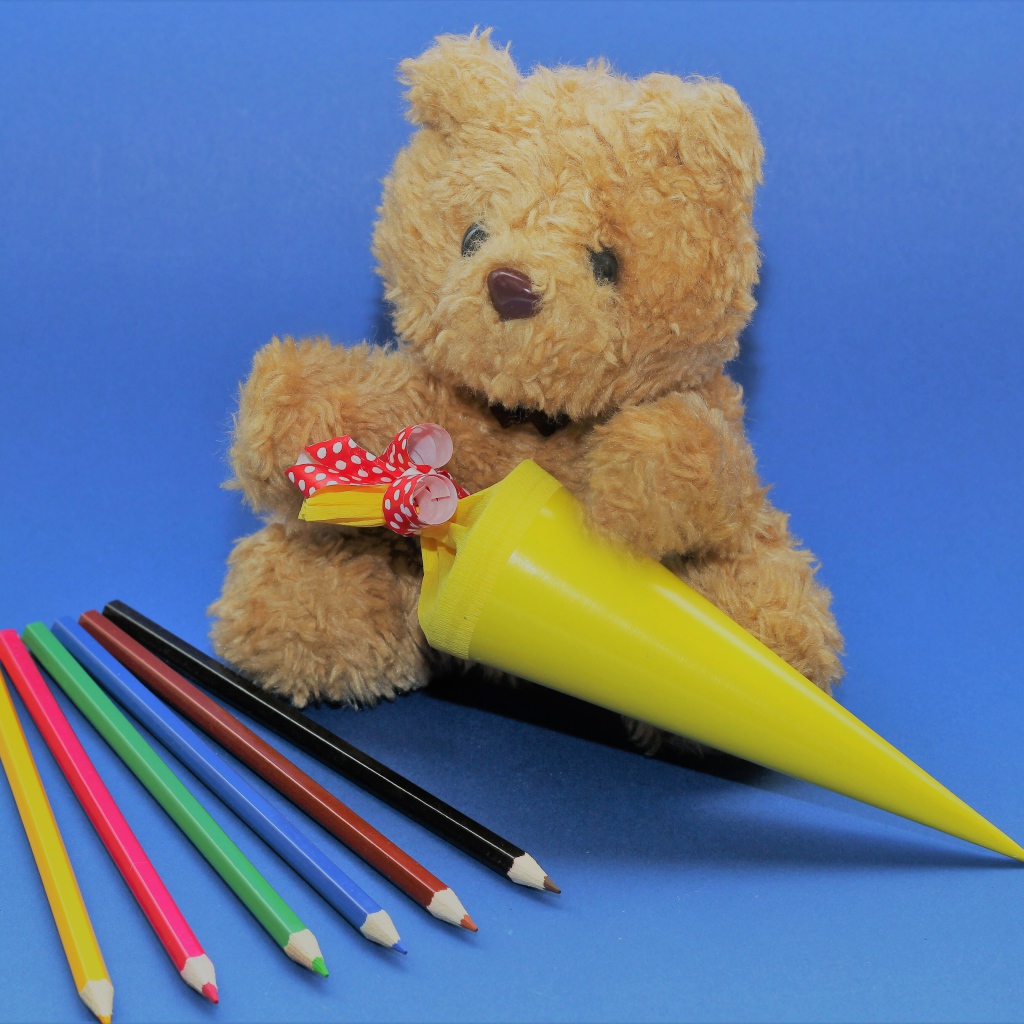 Teddy bear with pencils on blue background
