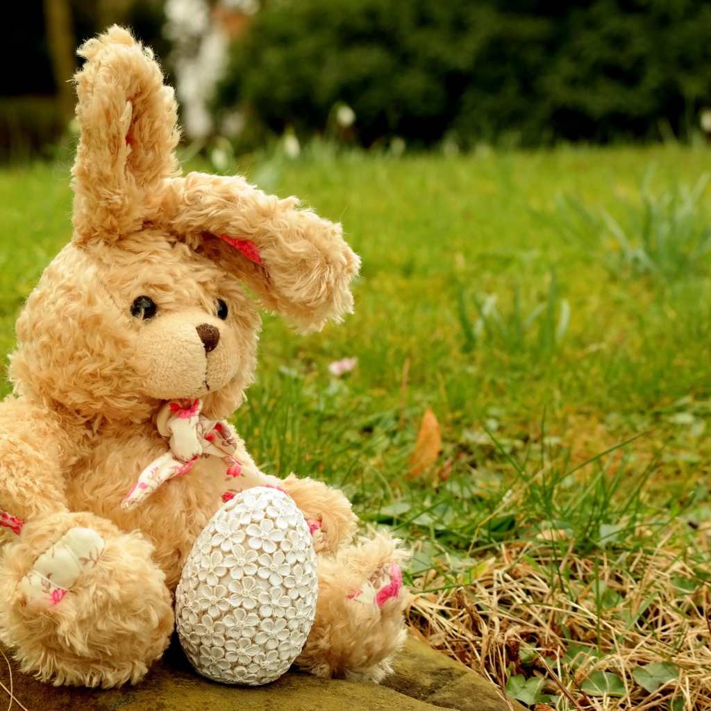 Игрушка заяц на камне в траве