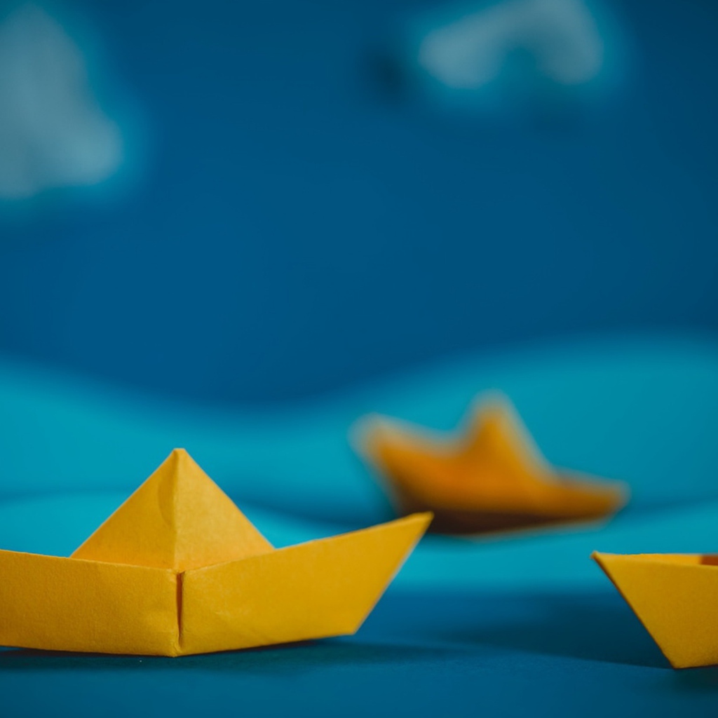 Желтые кораблики оригами на синем фоне