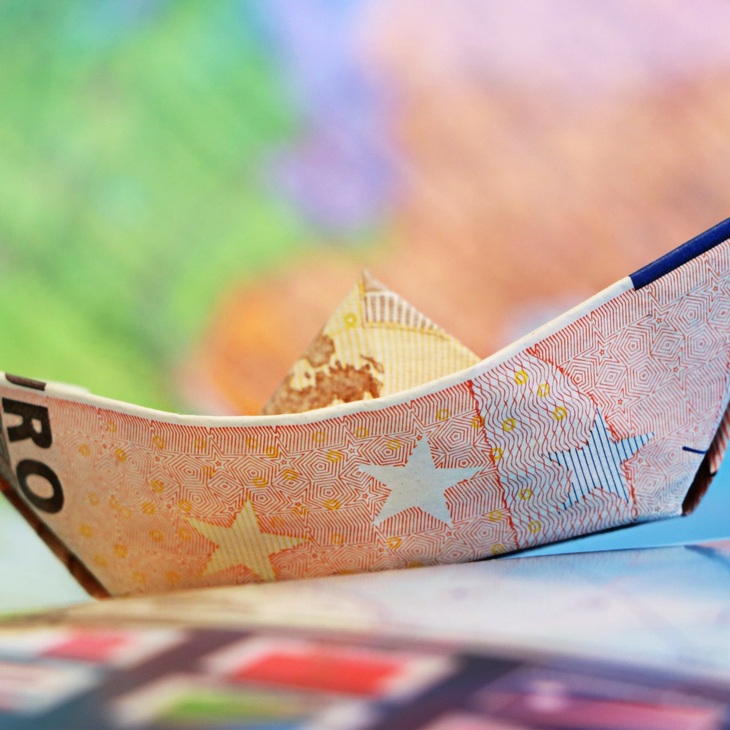 Кораблик из купюры евро на столе 