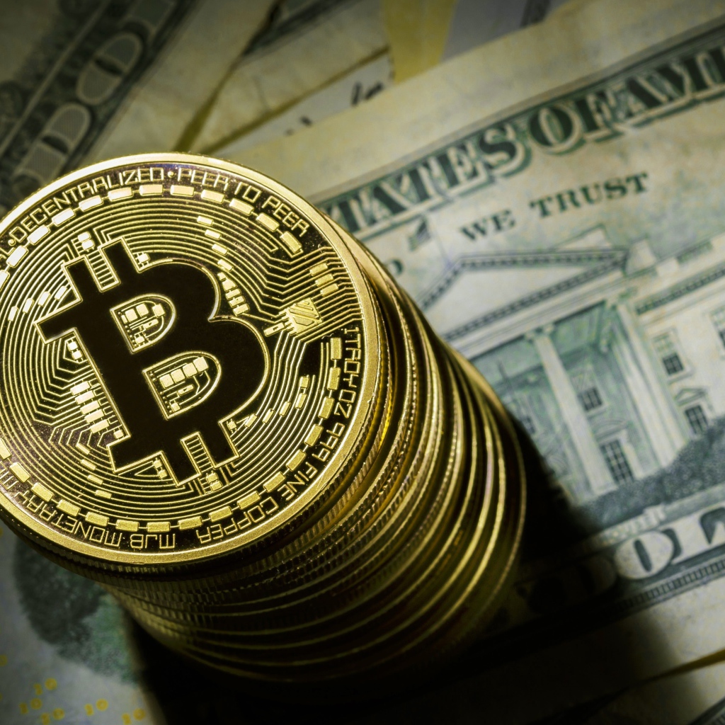 Золотые монеты биткоин лежат на долларах