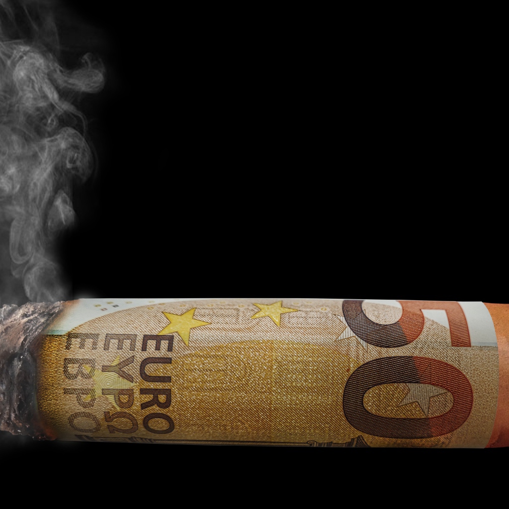 Сигара из купюры евро на черном фоне