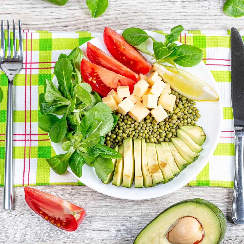 Аппетитные  свежие овощи с сыром и лимоном на тарелке 