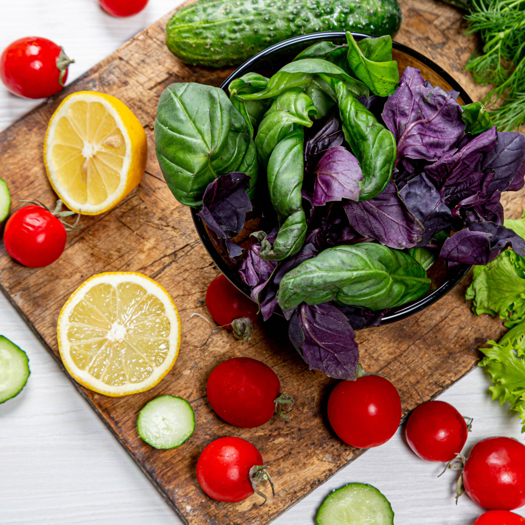 Базилик на столе с зеленью, помидорами и лимоном