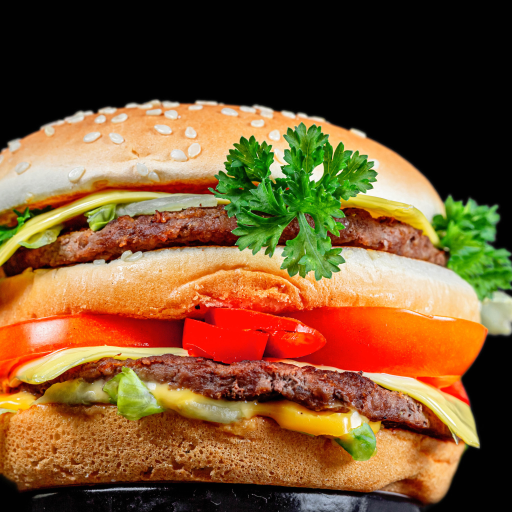 Большой гамбургер с котлетой на черном фоне