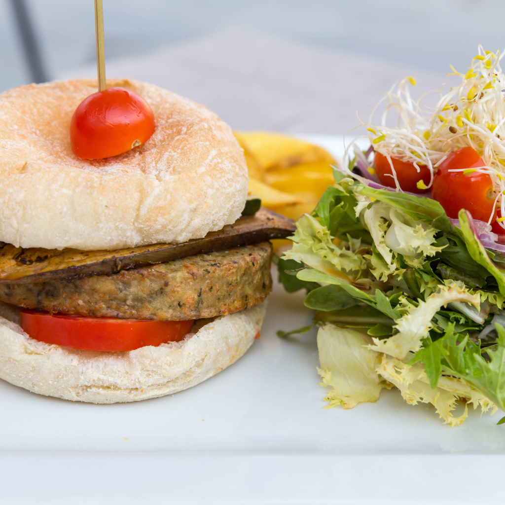 Большой гамбургер с салатом на столе 