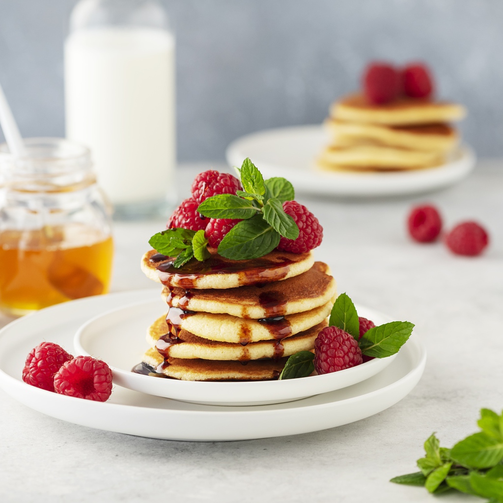 Румяные оладьи на тарелке с малиной и мятой 