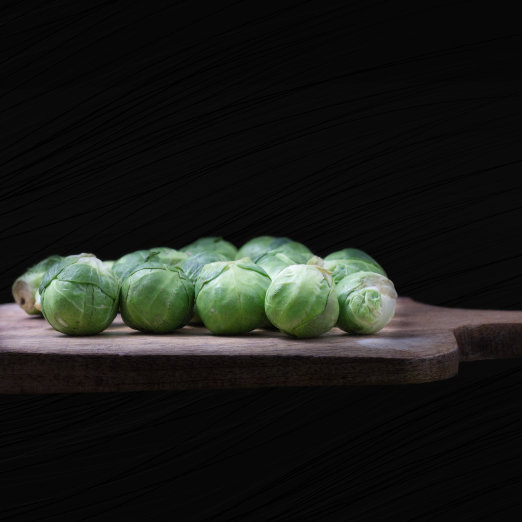 Брюссельская капуста на разделочной доске  на черном фоне