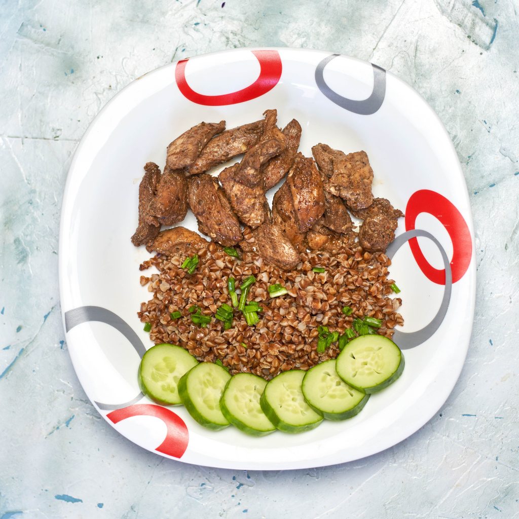 Гречка на тарелке с мясом и огурцами