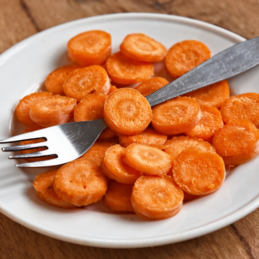 Морковь кружочками на белой тарелке с вилкой
