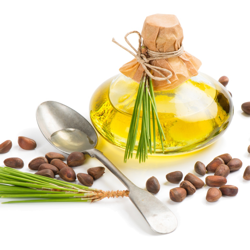 Кедровое масло на белом фоне с орехами и ложкой