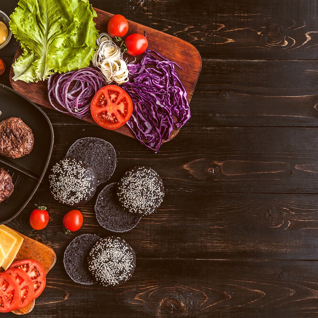 Повар готовит гамбургеры на деревянном столе