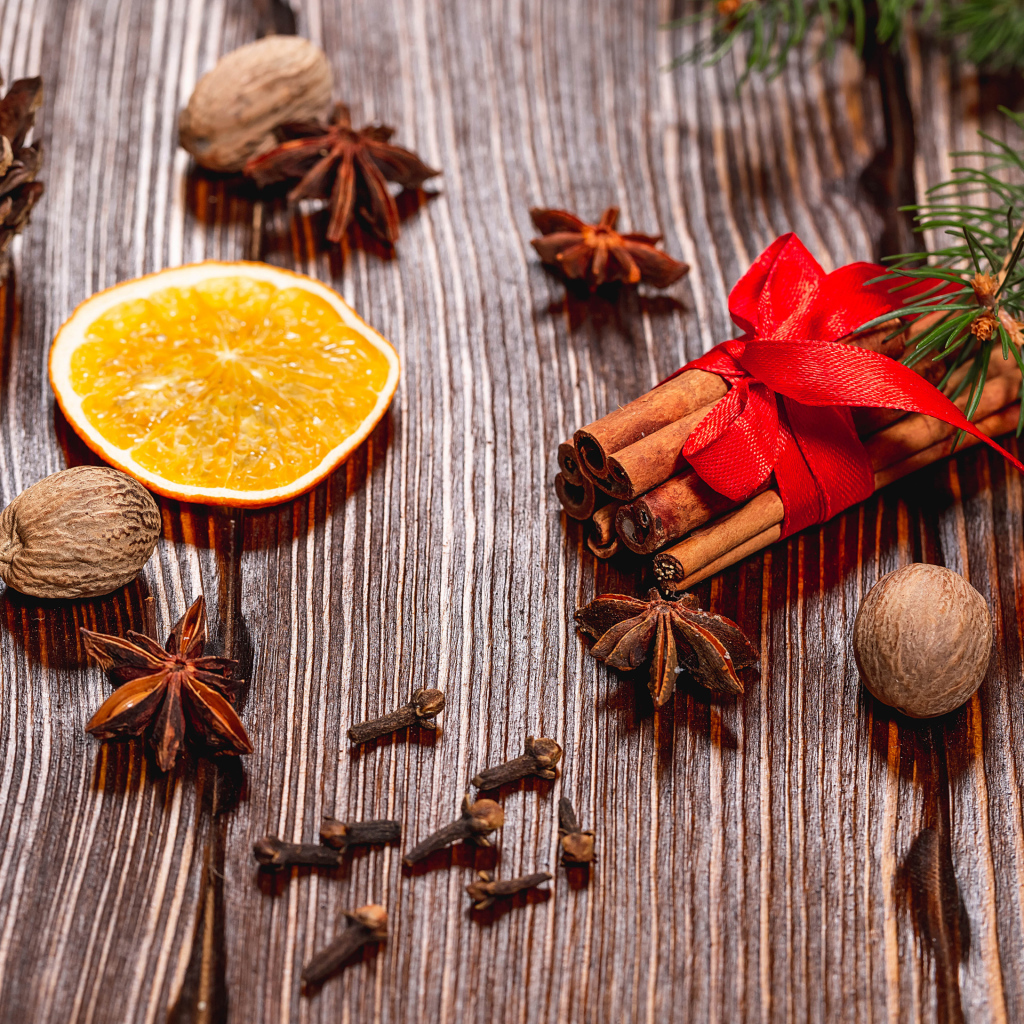 Корица на столе с орехами, бадьяном, сушеными апельсинами и гвоздикой
