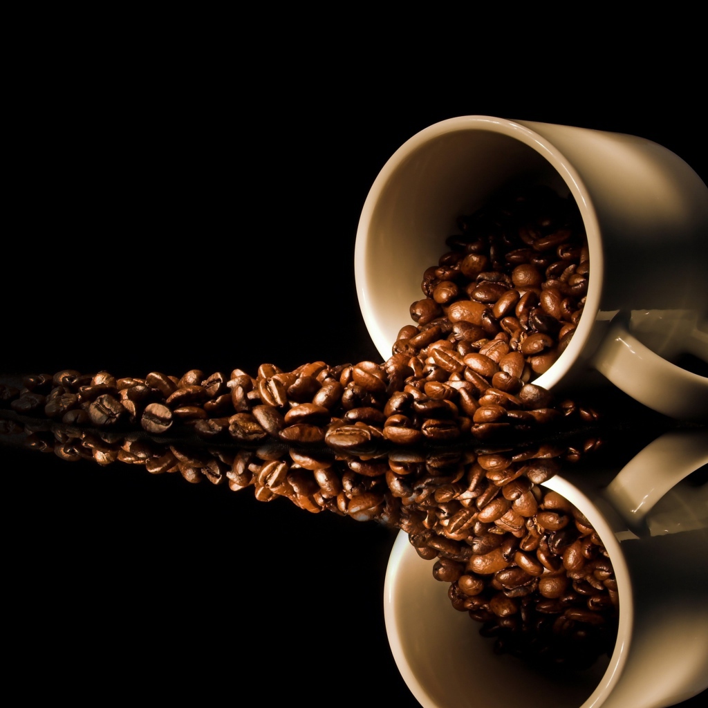 Кофейные зерна рассыпаны с белой кружки на стол