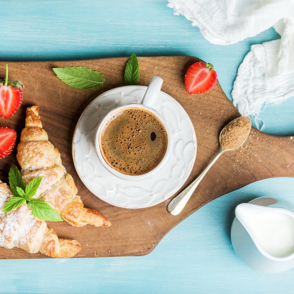 Чашка кофе на доске с клубникой и круассанами