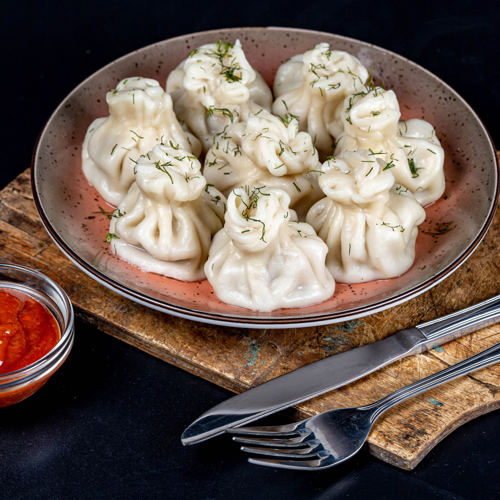 Вкусные горячие хинкали на столе с соусом