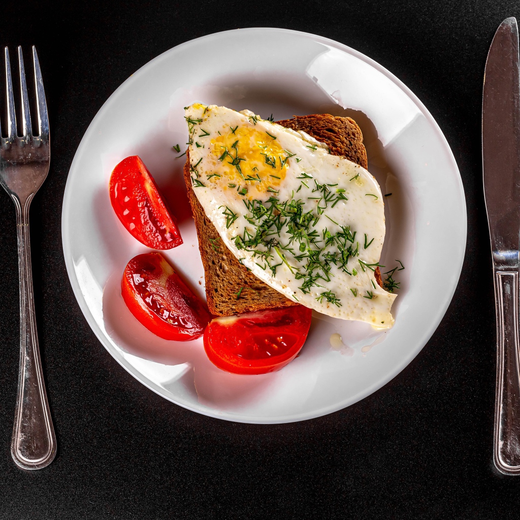 Бутерброд с яичницей на тарелке с помидорами